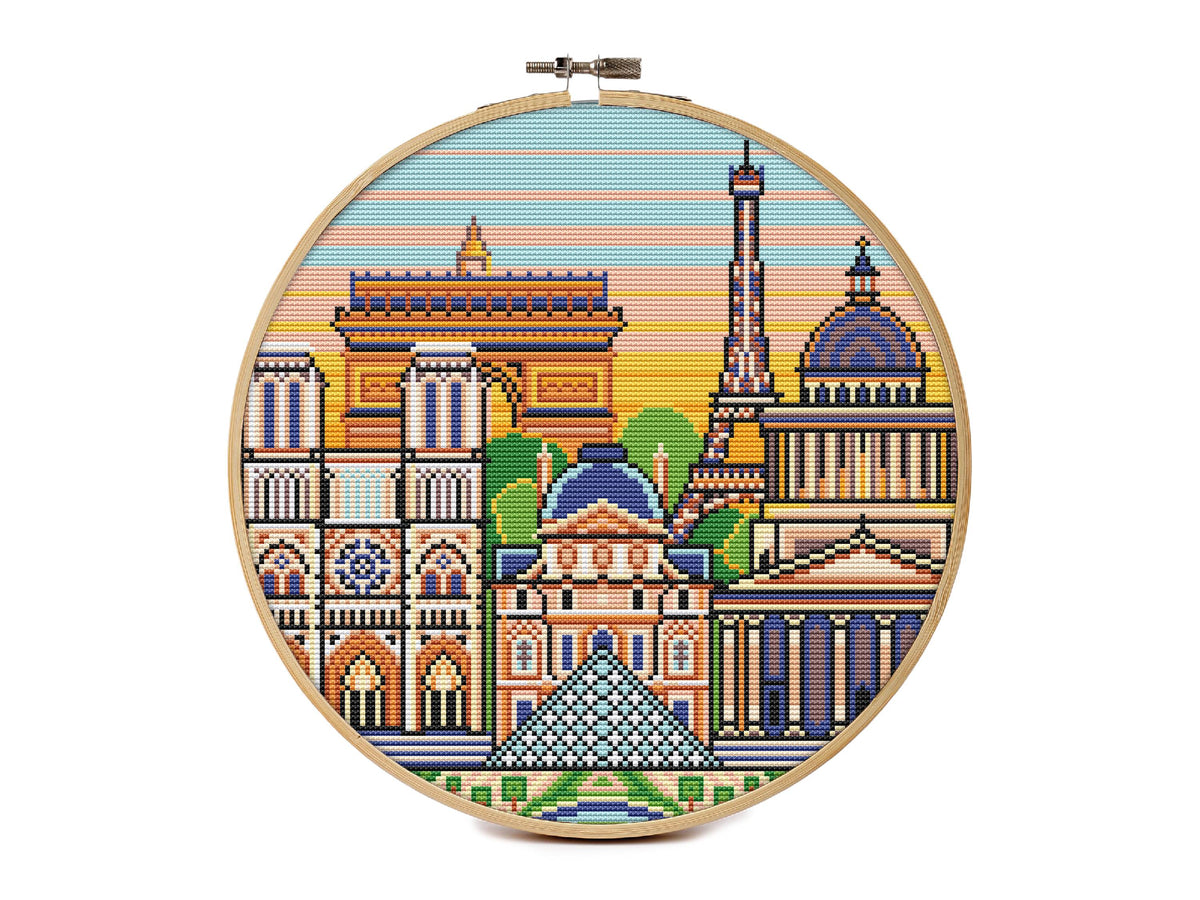 Round Paris cityscape cross stitch pattern showing the Eiffel Tower, Arc de Triomphe, Notre Dame, Louvre pyramid and domed buildings against a striped sunset sky.